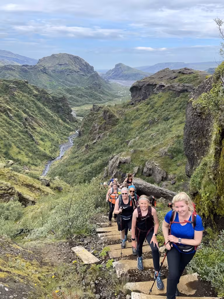 Group of women hikers ascending a lush green trail in Þórsmörk, showcasing Iceland's breathtaking natural beauty.