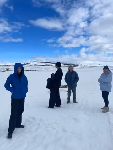 Women in winter gear explore the snowy Icelandic Highlands under a bright blue sky during a wellness retreat.