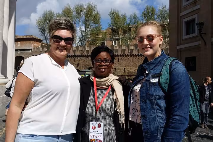 Three women pose outside Vatican Museum, showcasing friendly atmosphere of guided tours.