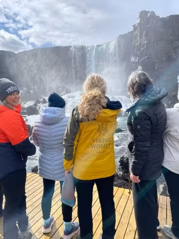 Group of women admiring a majestic waterfall in Iceland during a winter wellness retreat.