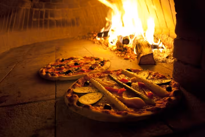 Two artisanal pizzas baking in a traditional wood-fired oven, capturing the essence of a Naples cooking class.