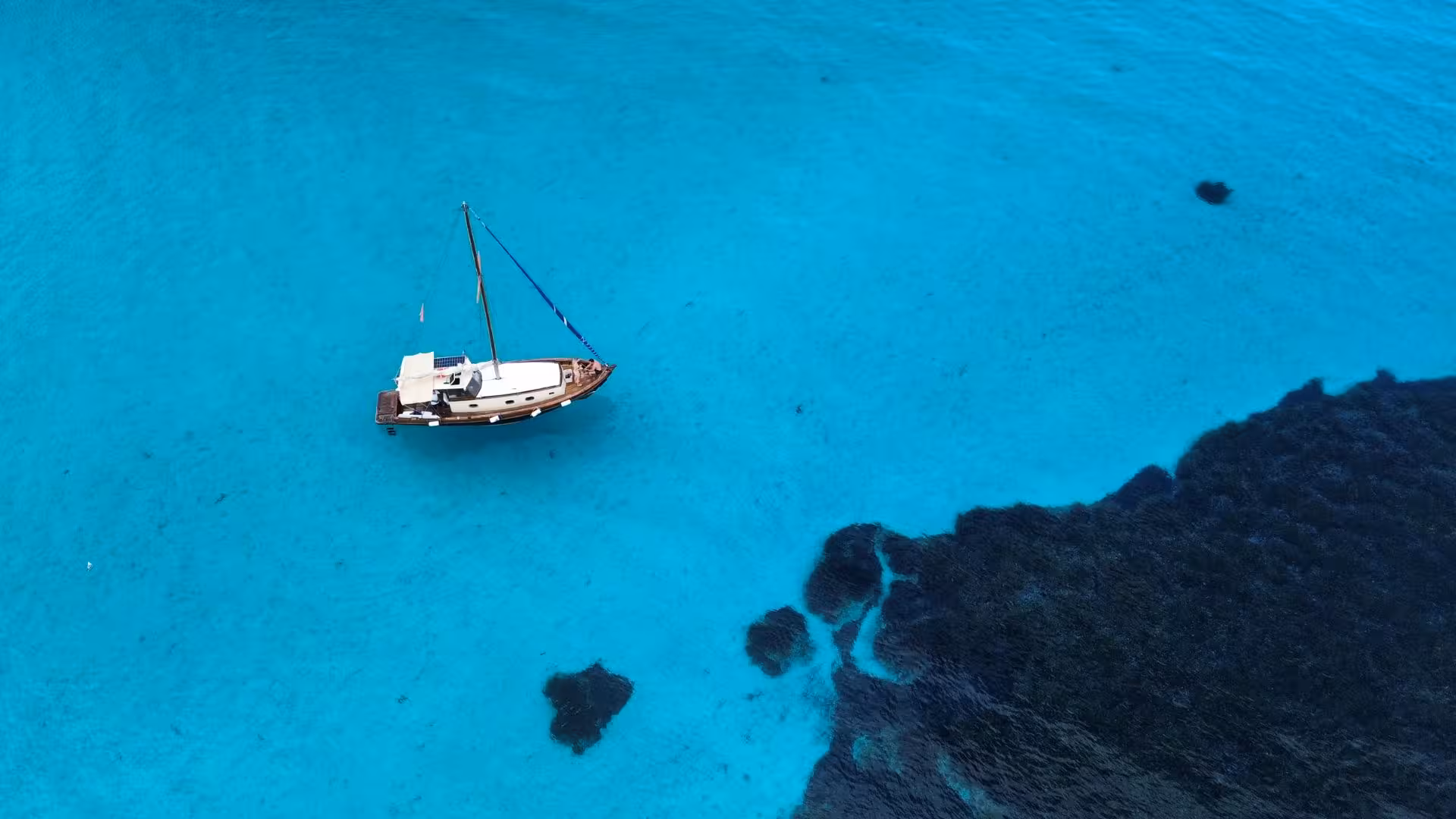 Aerial view of a wooden boat floating on crystal-clear waters near Asinara Island on a Stintino excursion.