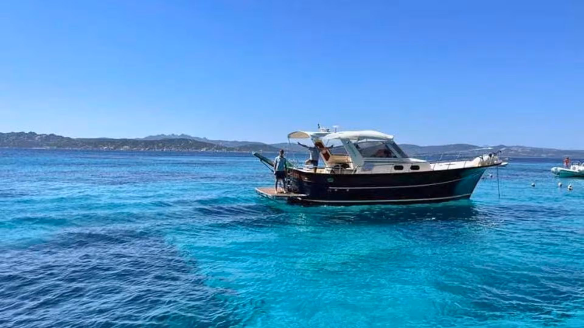Scenic view of a wooden boat on the crystal-clear waters of southern Corsica, perfect for Palau or La Maddalena tours.