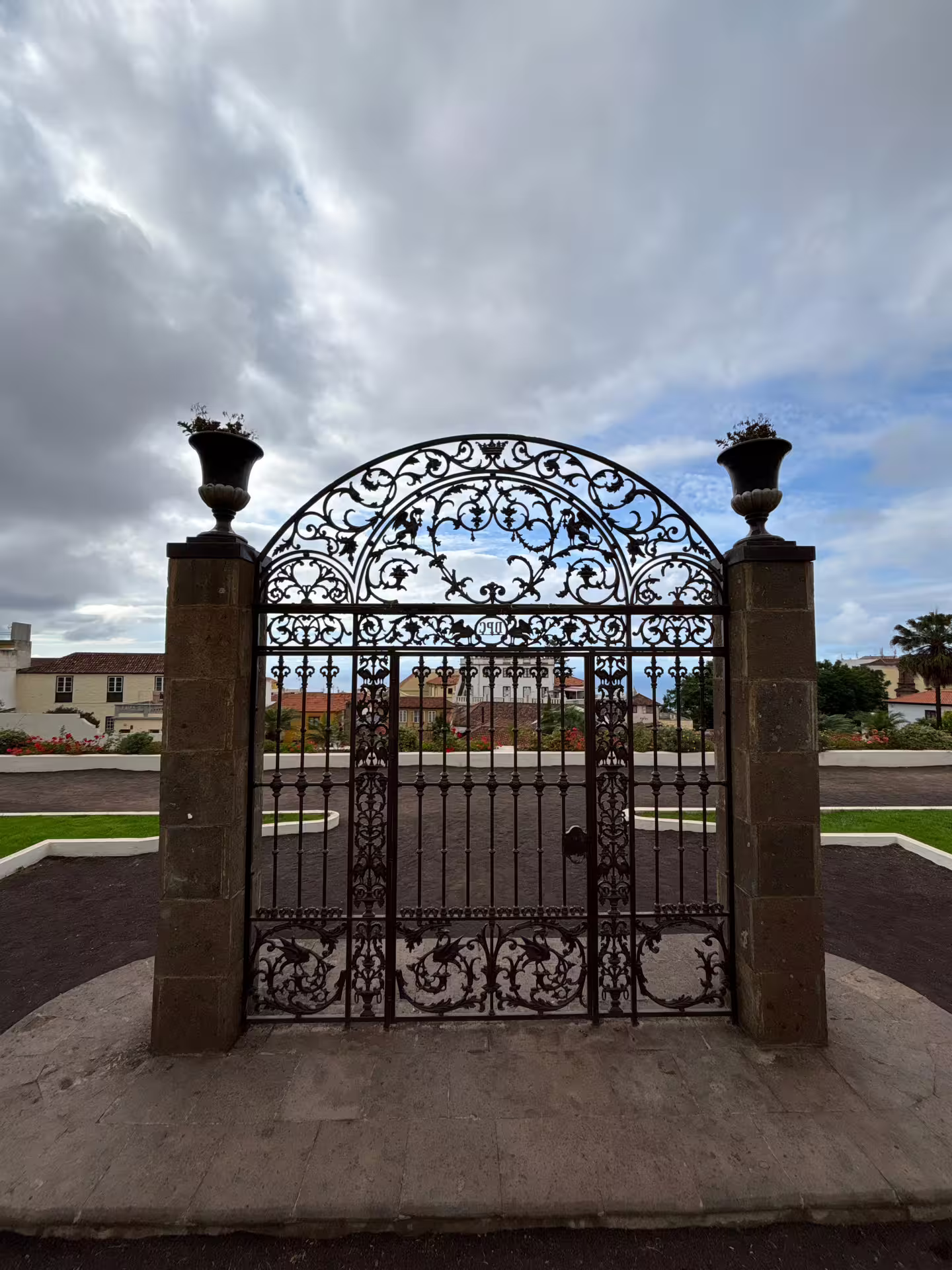 Ornate wrought iron gate with floral designs under a cloudy sky, ideal for cruise excursion photo ops.