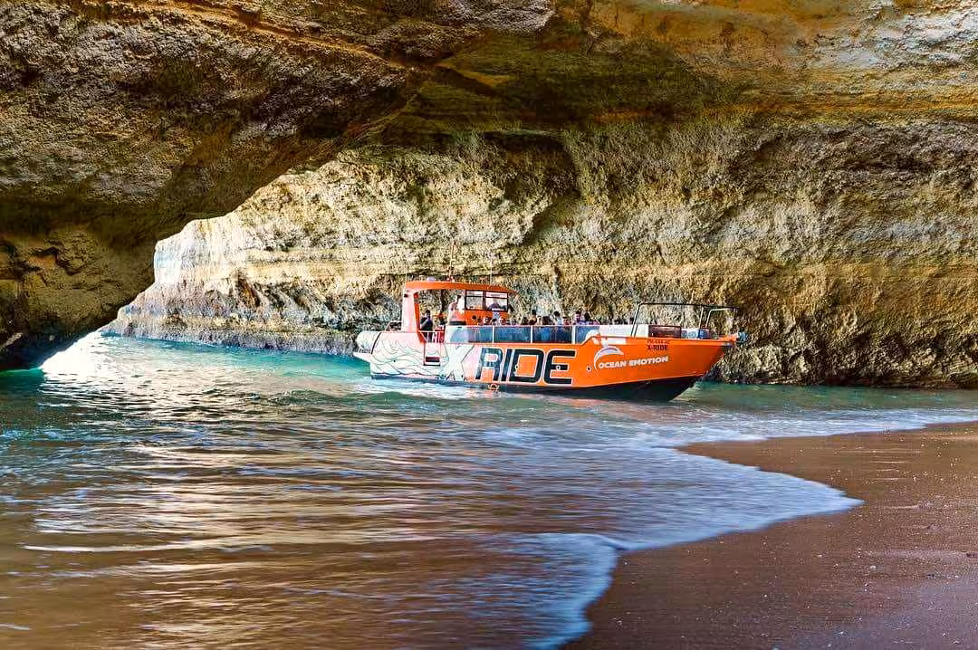 X Ride orange boat glides into Benagil sea cave, showcasing Algarve coastal cruise to hidden beaches and dolphins
