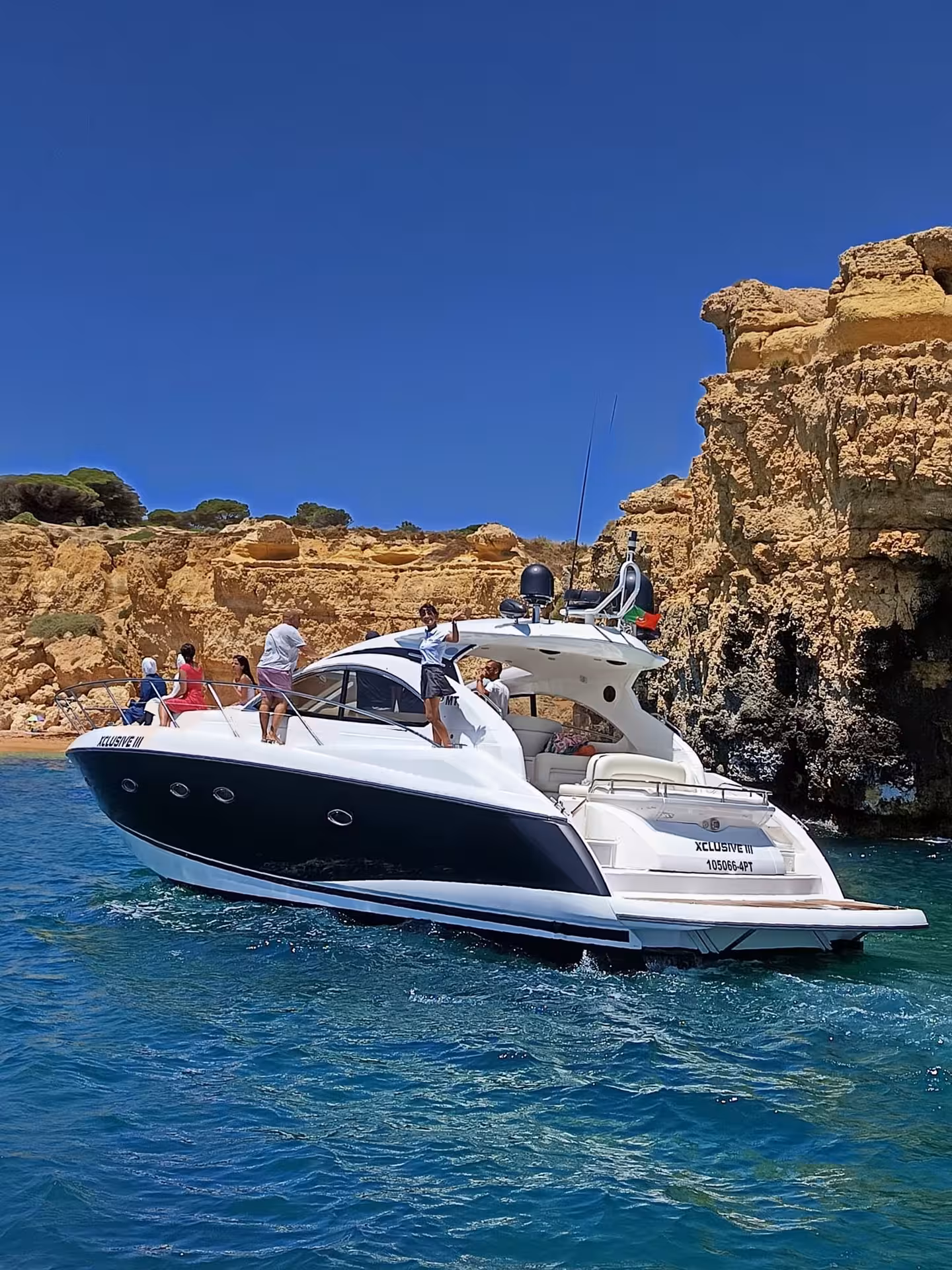 XCLUSIVE III Private Luxury Yacht cruising by golden Algarve cliffs on a sunny day with guests relaxing on deck
