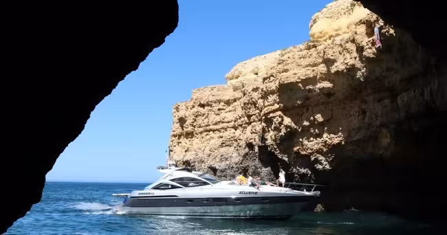 Xclusive Private Luxury Yacht glides through a dramatic Algarve sea cave, showcasing exclusive coastal cruise experience