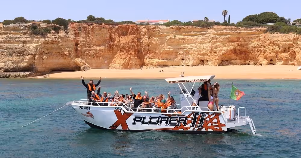 Group enjoying X Plorer Benagil caves and dolphins cruise off Algarve coast, passing golden cliffs and sandy beach