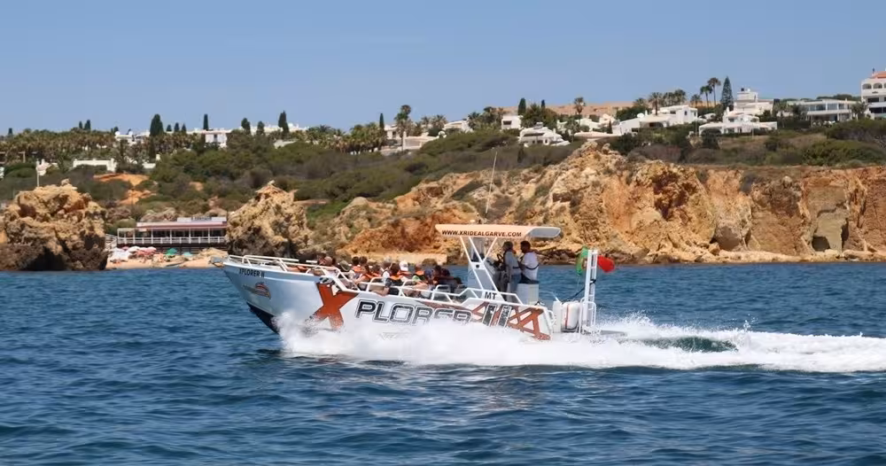 Speeding X Plorer dolphin watching boat off Algarve coast, passing Benagil-style cliffs and seaside resorts in Portugal