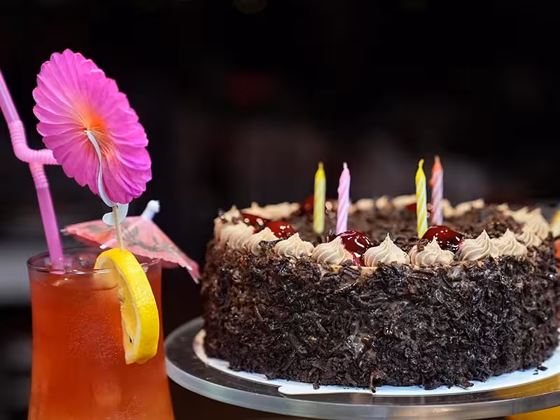 Birthday cake with candles and cocktail garnish, perfect dessert setup for a yacht birthday party cruise