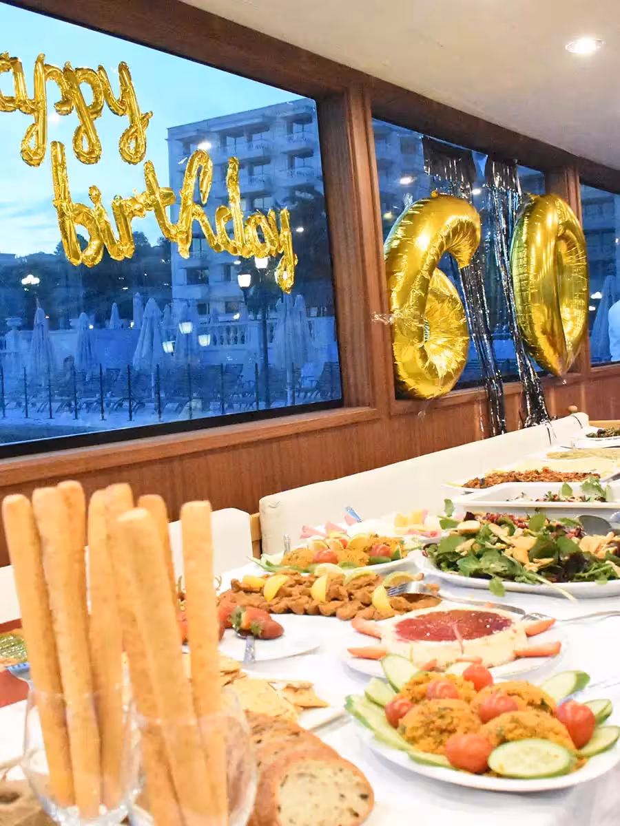Yacht birthday party buffet with appetizers and gold Happy Birthday 60 balloons inside luxury boat cabin