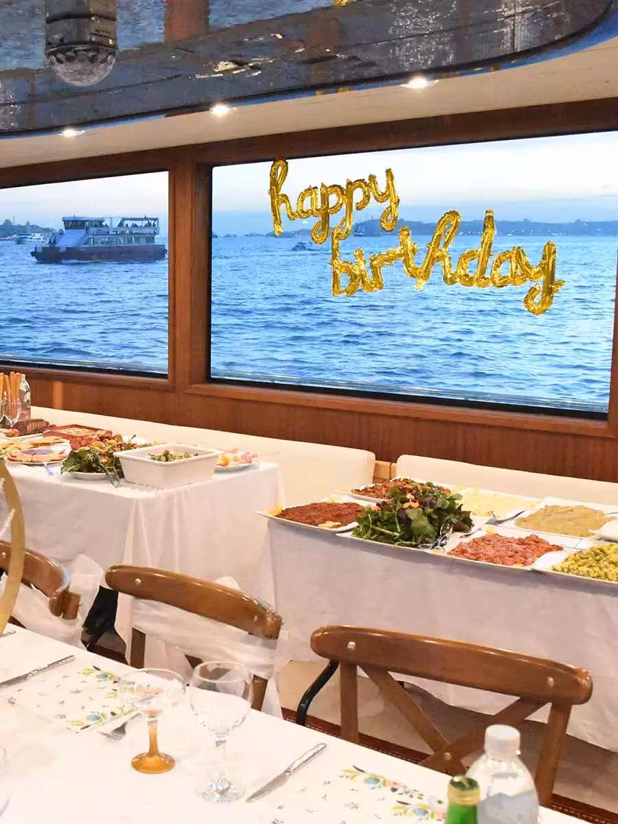 Yacht birthday party buffet setup with Happy Birthday balloons and sea-view windows on a private cruise