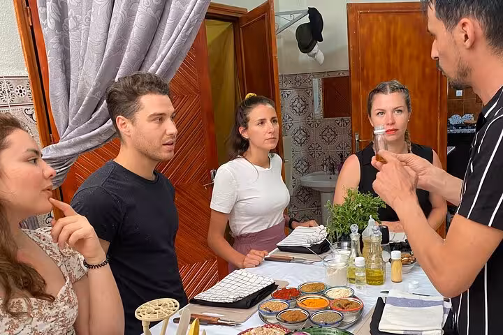 Yassine teaches a group about Moroccan spices during a hands-on cooking class experience.