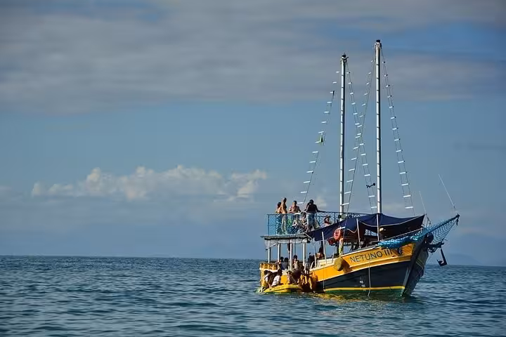 Yellow boat on calm sea with passengers enjoying Paraty Tours' scenic boat tour with lunch on board.