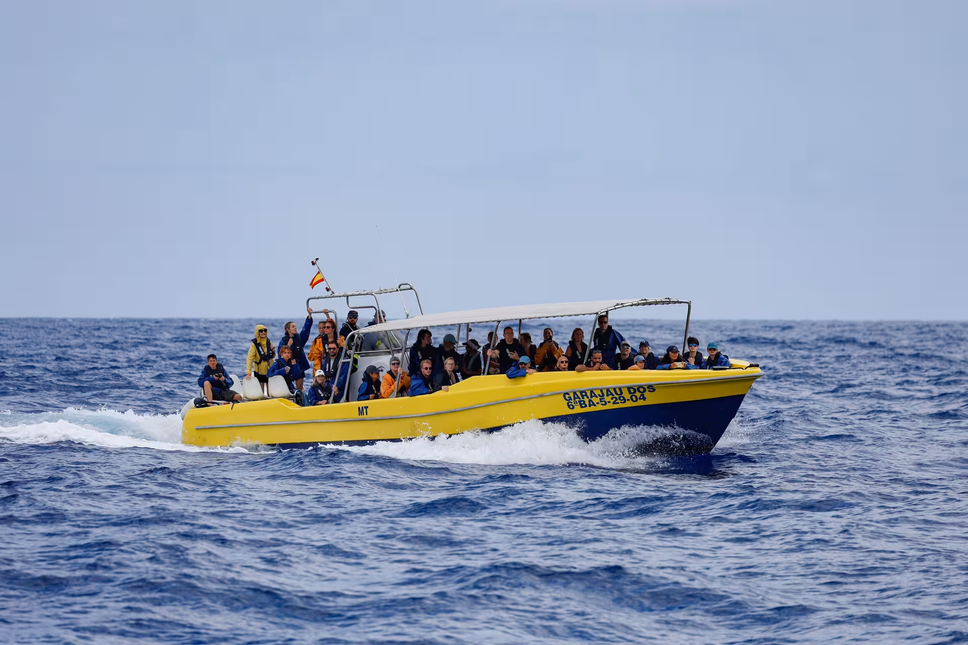 Yellow speedboat on half-day whale and dolphin watching cruise, passengers scanning the Atlantic for marine life