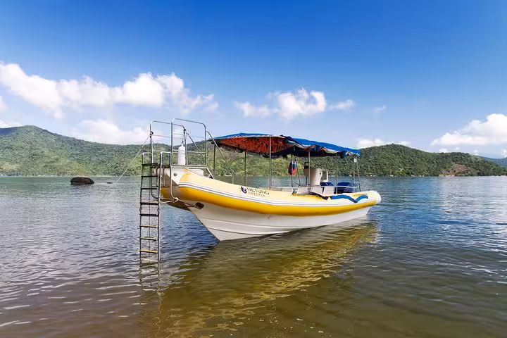 A yellow tour boat anchored in the tranquil waters of Saco Mamanguá Fjord, inviting exploration of idyllic beaches.