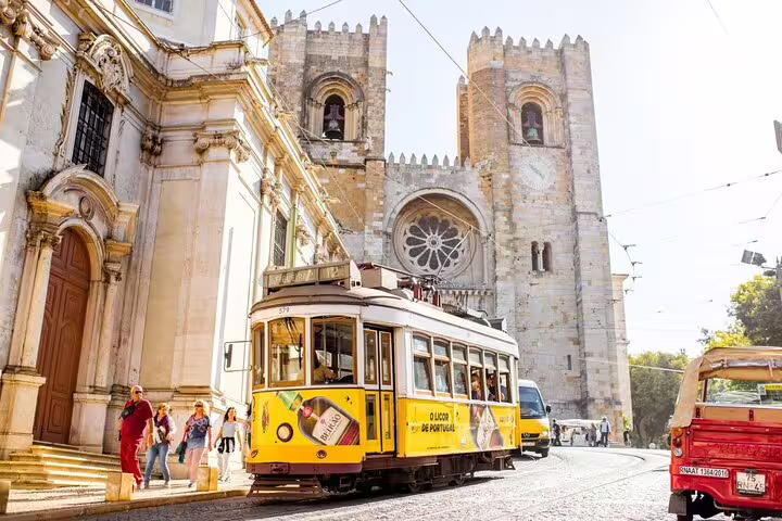 Yellow tram passing Lisbon Cathedral on a sunny day, capturing the charm of Lisbon's historic streets on a private walking tour.