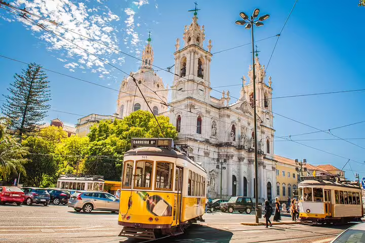 Yellow trams passing by the historical Basilica da Estrela in Lisbon on a sunny day, capturing the city's charm and culture.