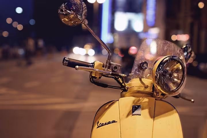 Yellow Vespa scooter parked on a vibrant Florence street at night, perfect for a stylish rental adventure.