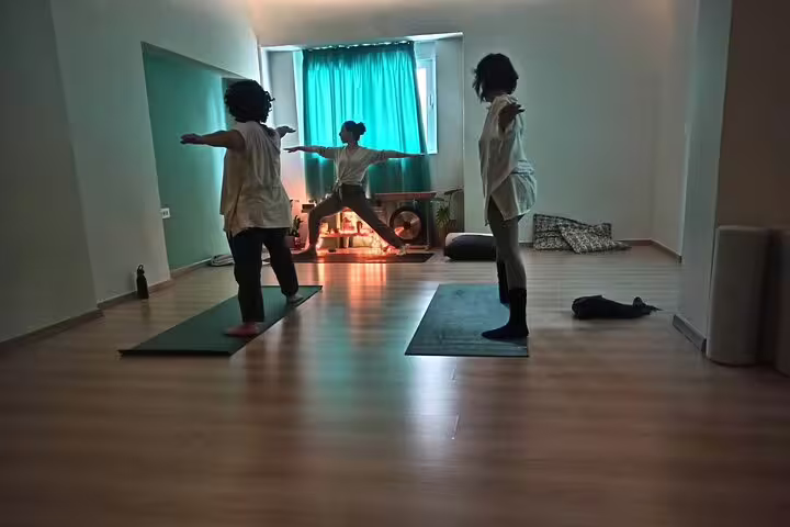 Small group in yoga class practicing warrior pose, enhancing strength and balance in cozy light-filled Kos studio.