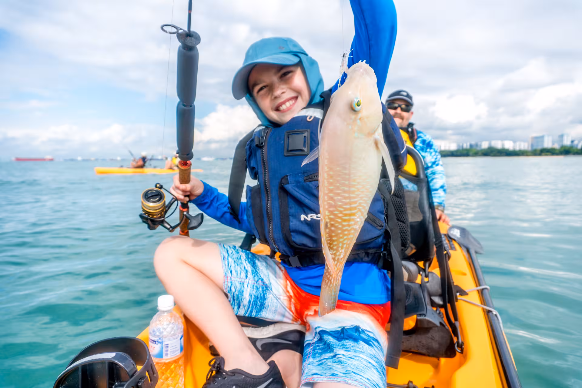 Young angler triumphantly holds a freshly caught fish during an exciting kayak fishing trip at East Coast.