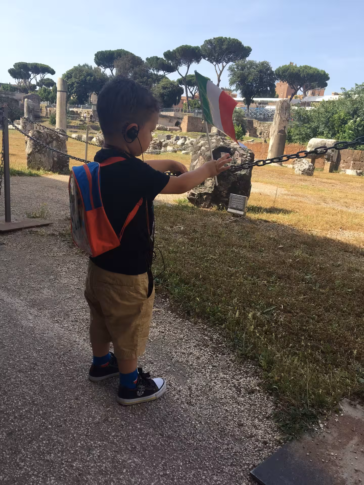 Young tourist with Italian flag exploring ancient ruins on the Colosseum Arena Combo Tour in Rome.