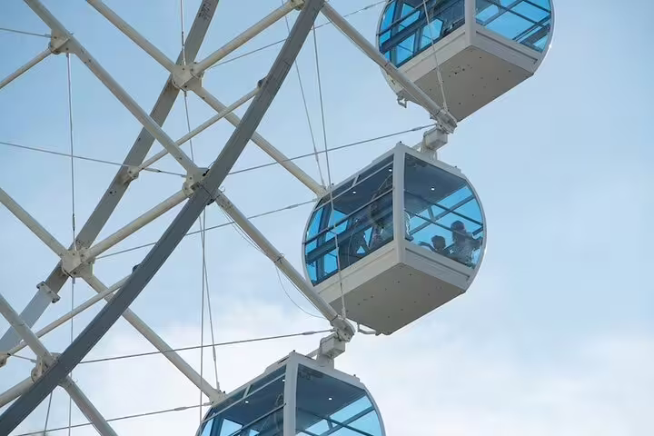 Close-up of Yup Star Ferris Wheel cabins with passengers enjoying panoramic views on a clear day.