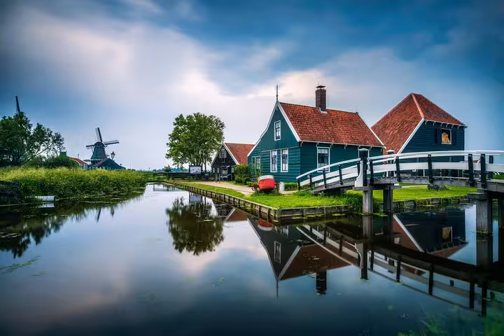 Zaanse Schans canal with traditional Dutch windmill and green houses on Discover The Netherlands tour from Amsterdam