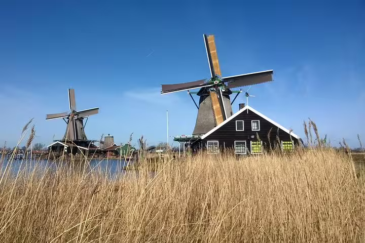 Zaanse Schans historic windmills by the canal with traditional house, Amsterdam to Volendam private day tour