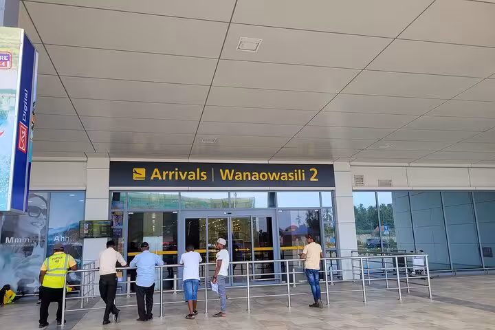 Zanzibar airport arrivals area with people waiting, ideal for private transfer to East Coast hotels.