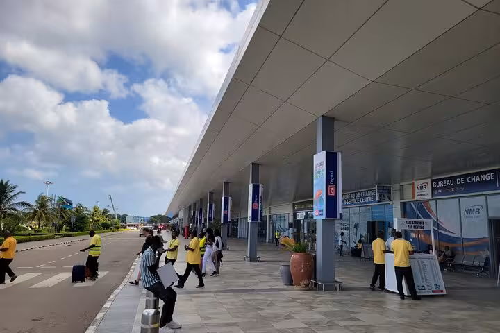 Zanzibar Airport entrance bustling with travelers, the starting point for private transfer services to East Coast hotels.