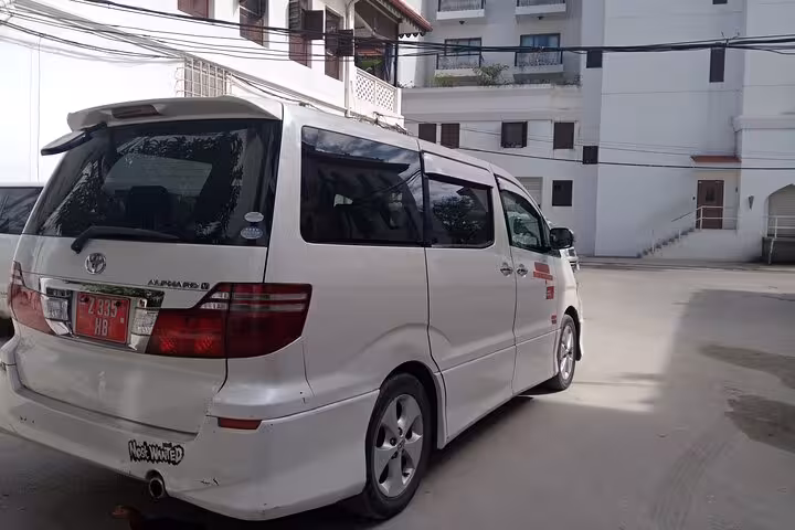 Private transfer minivan parked in a residential area of Zanzibar, perfect for hotel and airport commutes.