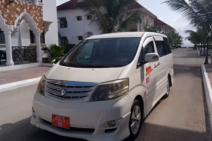 Spacious white shuttle van for Zanzibar Airport Transfers parked near a resort, ideal for comfortable island travel.