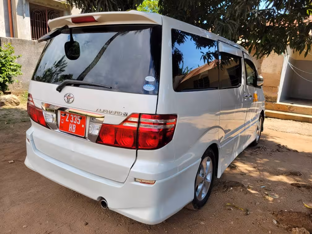 White Toyota Alphard minivan parked under a tree, ideal for private airport transfers to Pongwe hotels in Zanzibar.