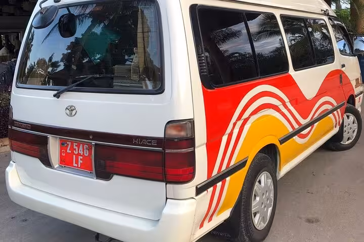 Rear view of vibrant tour van with red and yellow stripes for Zanzibar private airport transfers.