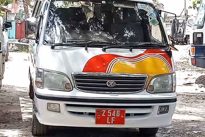 Front view of colorful van for Zanzibar airport transfer service with unique red and yellow design.