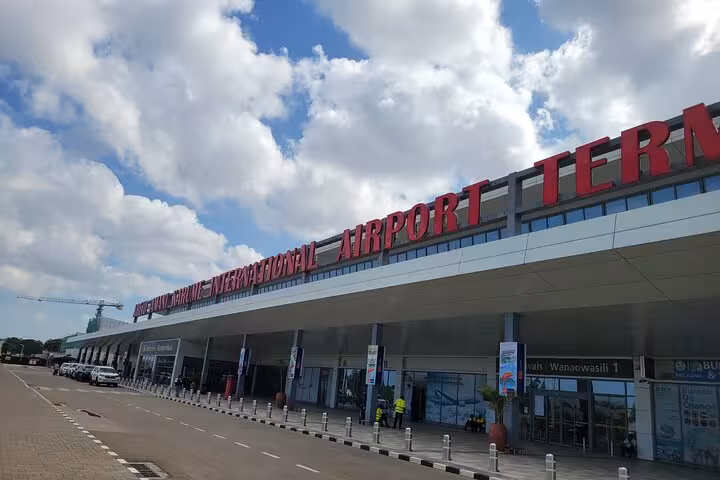 Exterior view of Abeid Amani Karume International Airport's modern terminal under blue skies.