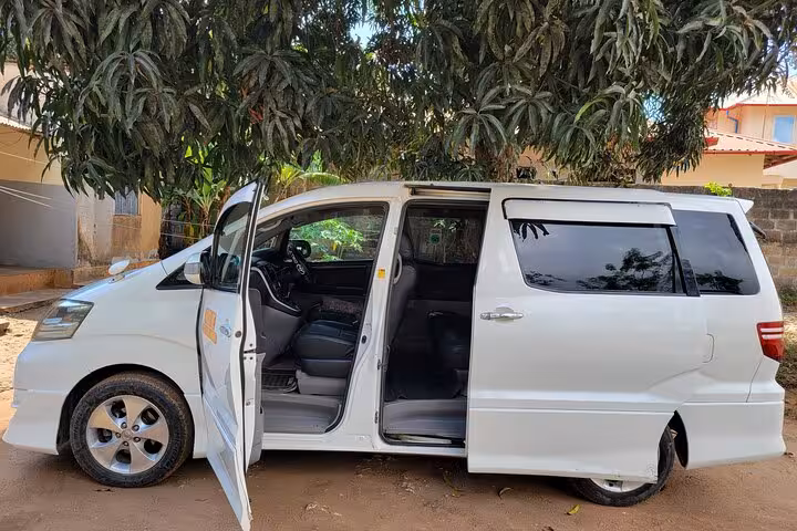 White minivan with open doors ready for private transfer from Zanzibar airport to East Coast hotels.