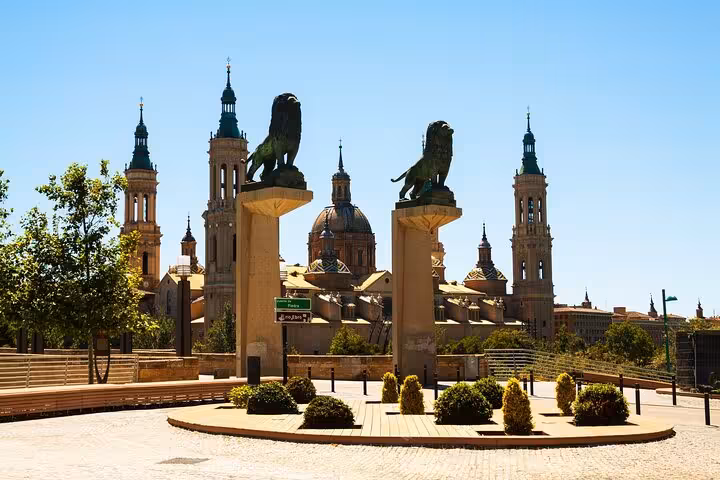 The majestic lion statues at Puerta del Pilar with the Basilica de Nuestra Señora del Pilar in the background in Zaragoza.