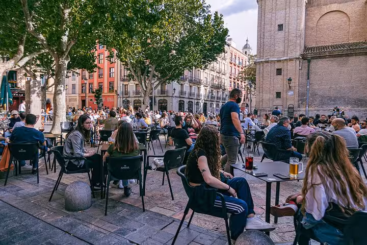 Bustling outdoor cafe scene in Zaragoza's historic center, with people enjoying drinks and vibrant street life.