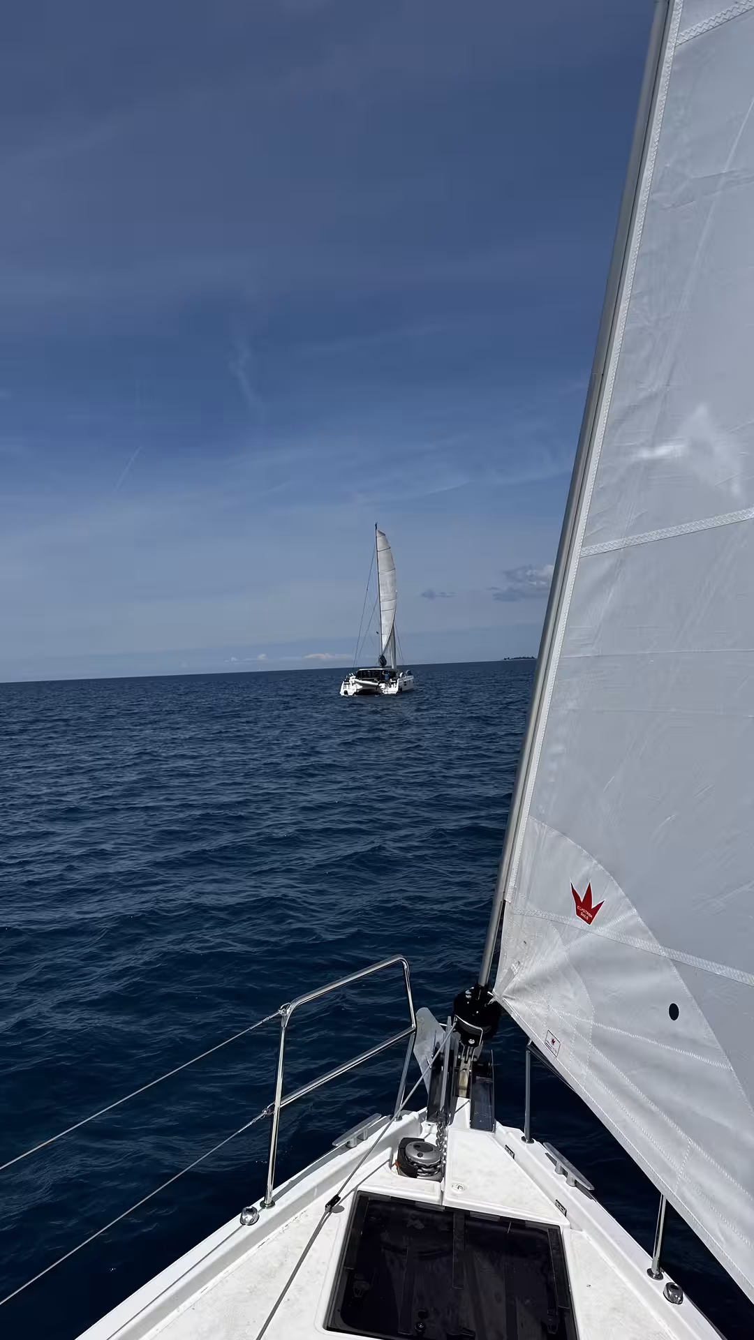 View from sailboat bow with mainsail up, cruising open water on Zero to Hero sailing training tour