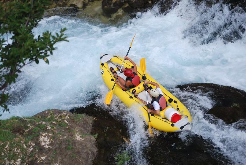 Adventurous duo navigating the thrilling Zrmanja River rapids in a yellow canoe during an exciting safari tour.