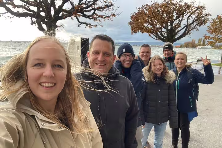 Group smiling on Zug lakeside promenade on a self-guided scavenger hunt tour with scenic Lake Zug views
