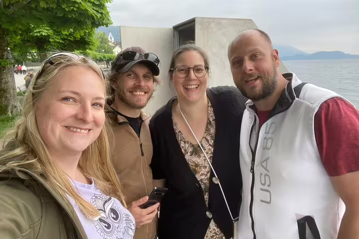 Happy travelers selfie at Lake Zug waterfront while playing a Zug scavenger hunt and sights self-guided tour