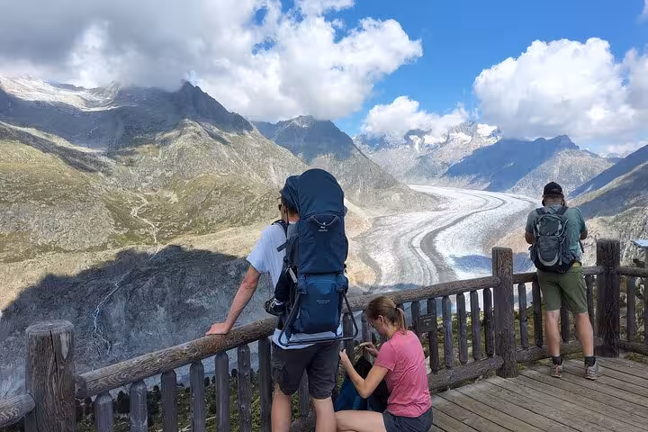Travelers at a viewpoint deck with backpacks, admiring Aletsch Glacier scenery on a Zurich day tour