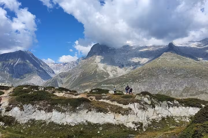 Hikers on rocky ridge with sweeping Swiss Alps views on Zurich day trip to the Aletsch Glacier area