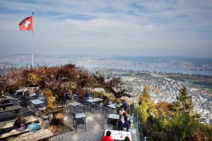 Outdoor cafe with Swiss flag, offering stunning views of Zurich city and lake from a half-day tour with cable car.