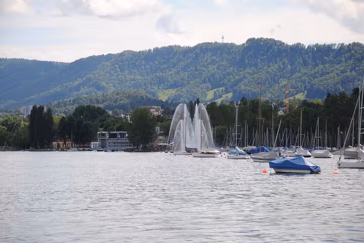 Lake Zurich fountain and sailboats with Uetliberg hills, scenic stop on Zurich 360 city walk tour