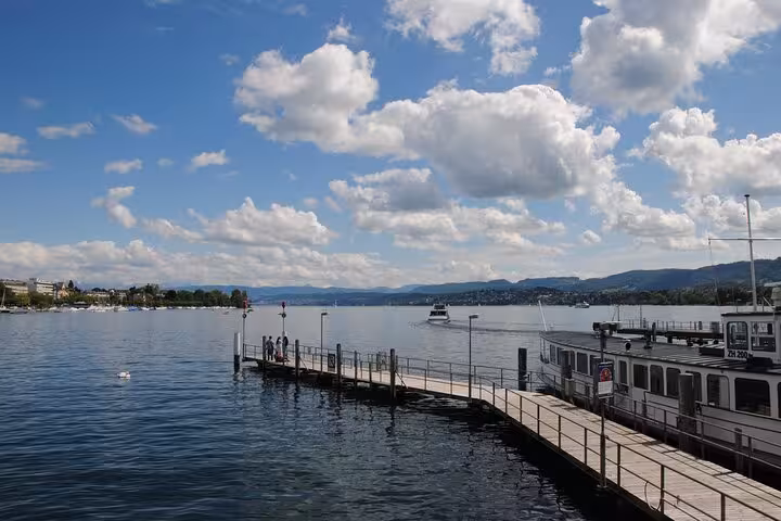 Lake Zurich pier with boats and Alps views, scenic stop on the Zurich 360 City Walk Tour including hidden spots