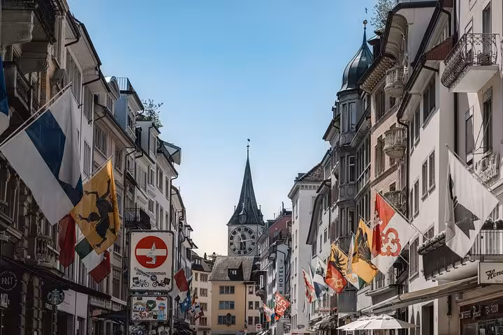 Zurich Old Town street with flags and St. Peter Church clock, 360 city walk tour hidden spots